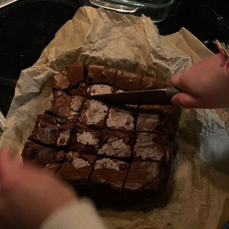 someone cutting into a brownie on top of wax paper