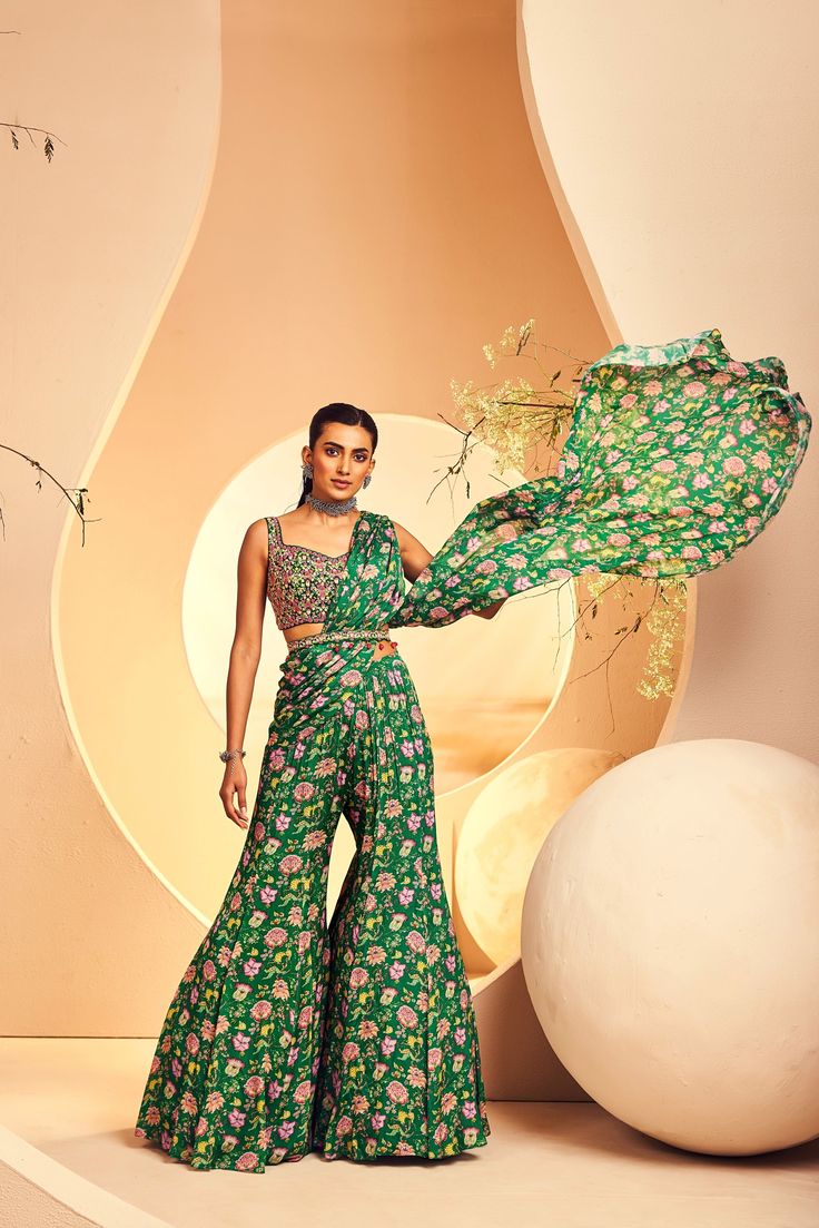 Featuring a botanical floral printed sharara-styled pre-stitched sari which is paired with a fully hand-embellished blouse. The blouse is embroidered with intricate Japanese beads and cutdana embroidery. The belt is accentuated with ruby-coloured drop stones. From Aneesh Agarwaal's Naksh collection. DELIVERY TIMEPlease allow 8-12 weeks for your outfit to arrive. FABRIC DETAILSChinon Chiffon Professional cleaning only. Green Art Silk Saree-style Palazzo Set, Georgette Palazzo Set With Printed Motifs For Reception, Anarkali Silk Saree With Floral Embroidery, Bollywood Style Saree Palazzo Set With Floral Embroidery, Silk Anarkali Pre-draped Saree With Floral Embroidery, Anarkali Pre-draped Silk Saree With Floral Embroidery, Traditional Sharara With Floral Print For Receptions, Traditional Floral Print Sharara For Reception, Green Floral Sharara For Navratri