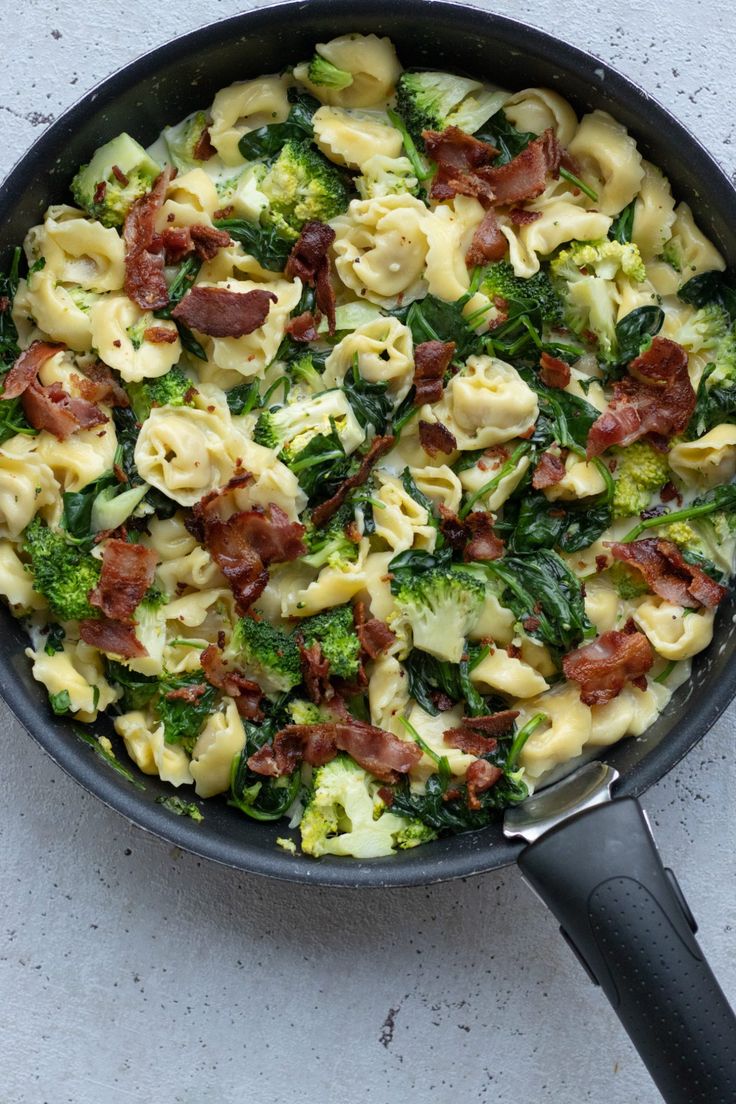 a skillet filled with pasta, broccoli and bacon