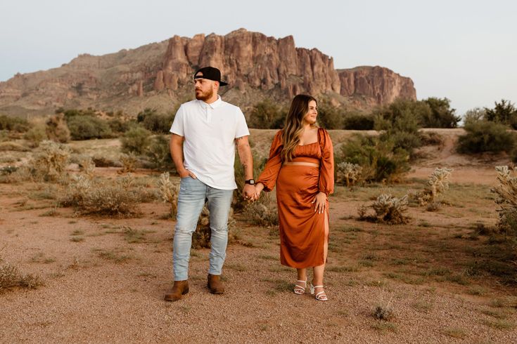 a man and woman walking in the desert holding hands