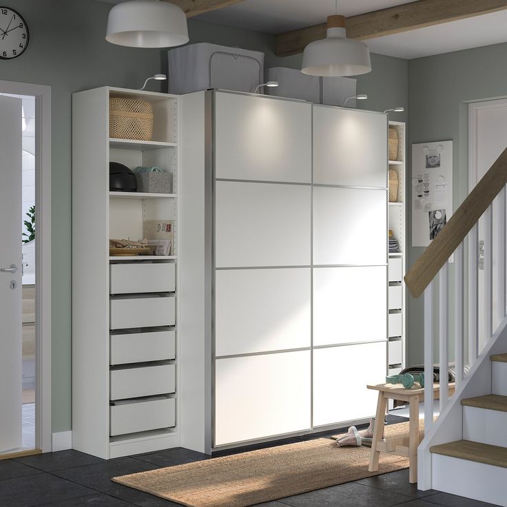 a white cabinet with drawers and shelves in a living room next to a stair case