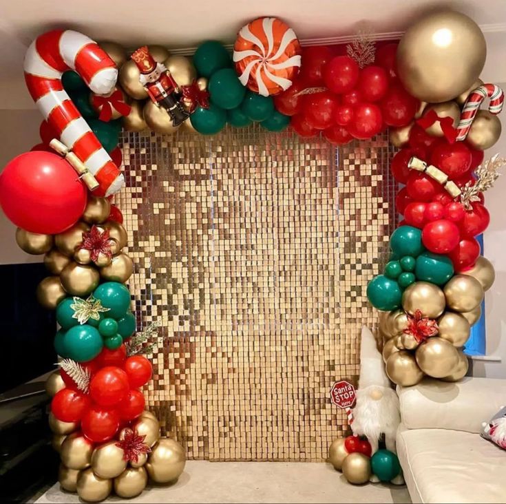 an arch made out of balloons, candy canes and christmas decorations is displayed in front of a couch