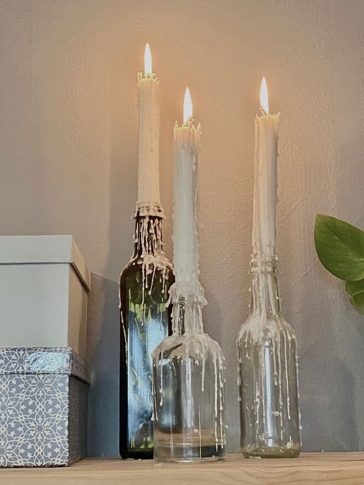 three candles are sitting on a shelf next to bottles