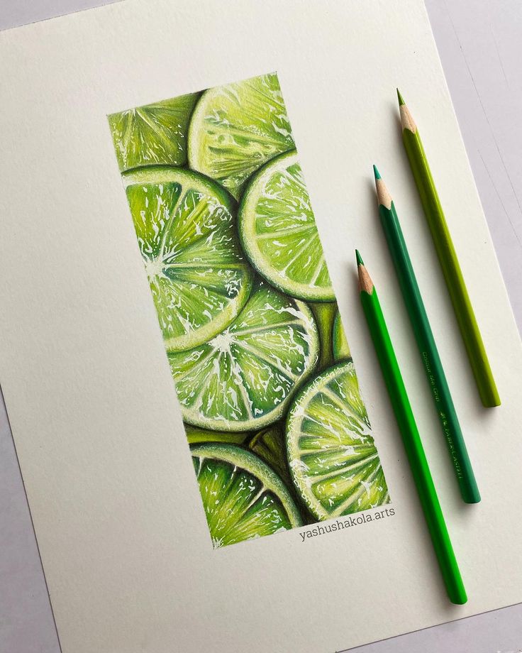 two pencils are next to a drawing of lime slices