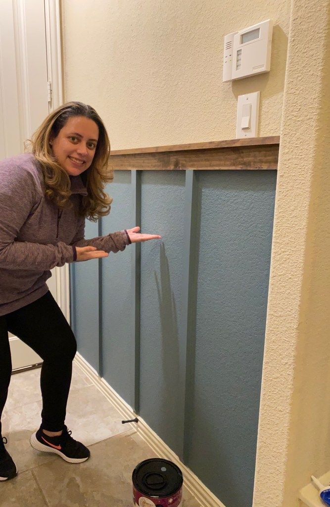 a woman standing in front of a blue wall pointing at something on the floor next to her