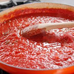 a wooden spoon in a saucepan filled with tomato sauce