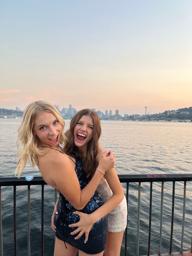 two women standing next to each other near the water