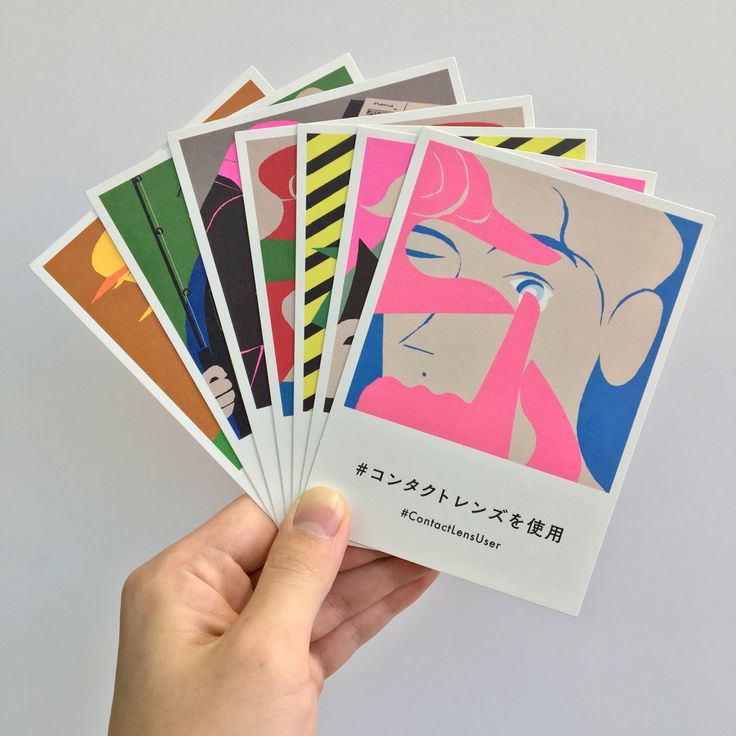 a hand holding five different colored cards with japanese characters on them in front of a white background