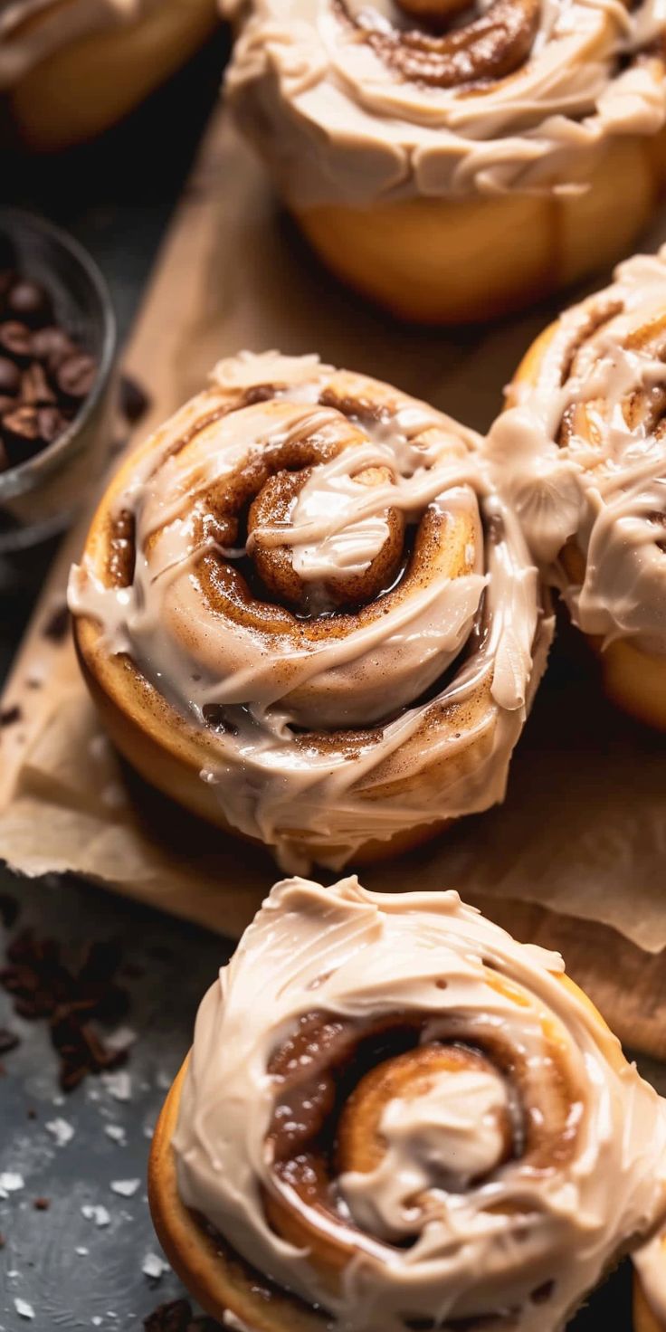 several cinnamon rolls with frosting on top of brown paper and chocolate chips around them