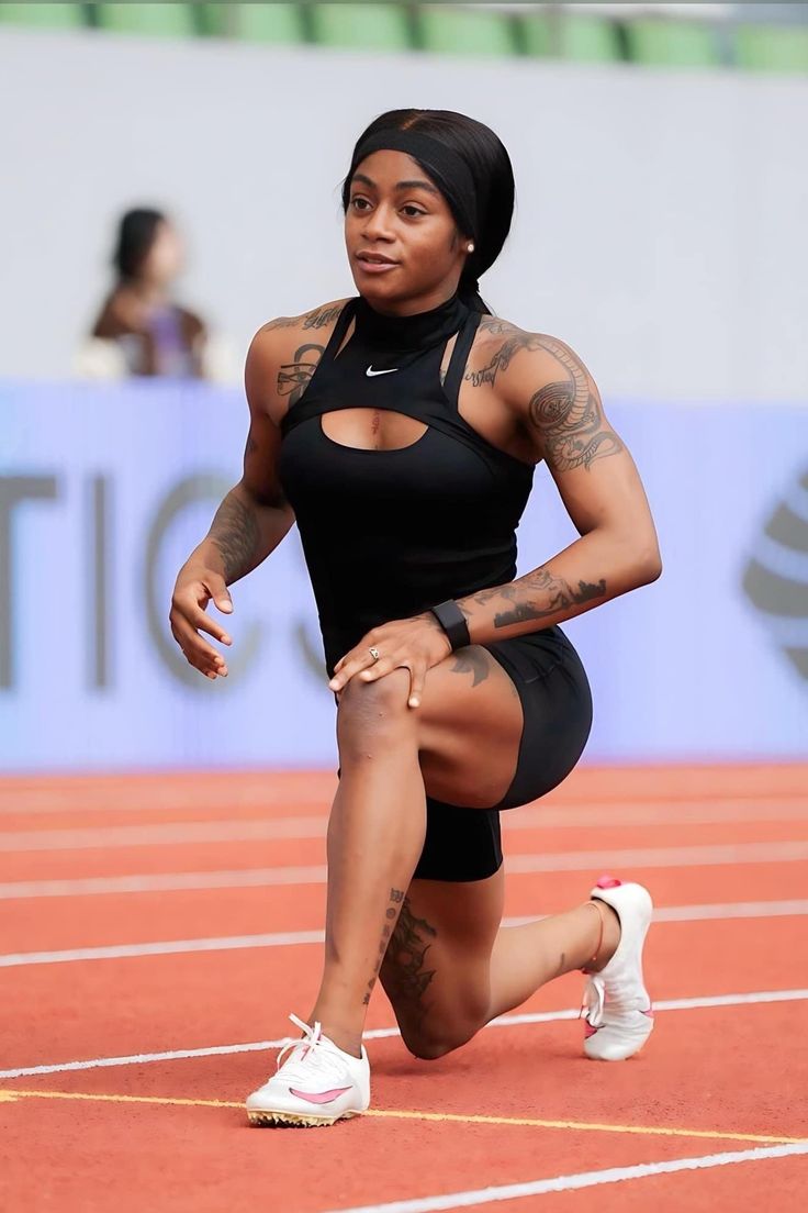 a woman kneeling down on a track with her legs crossed and one hand in the air