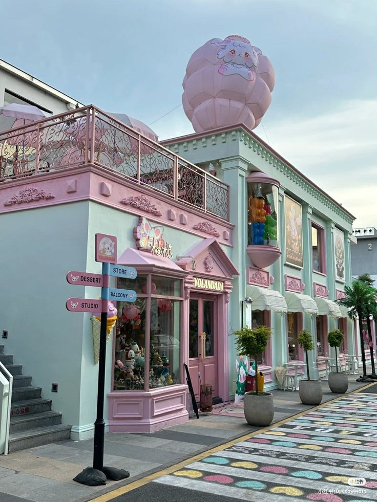 a pink and white building with lots of windows on the side walk in front of it