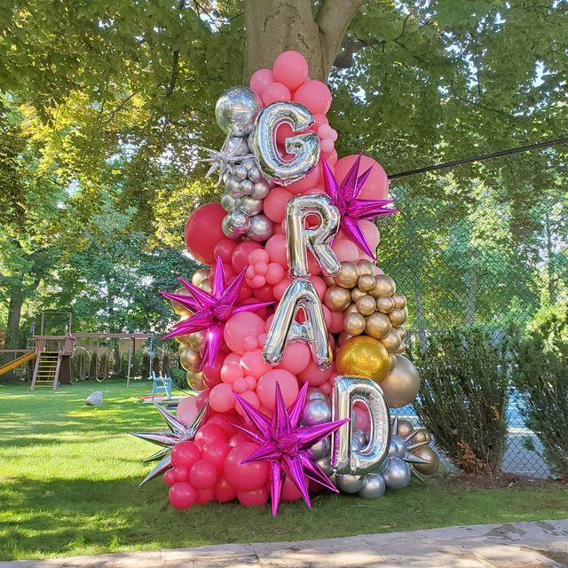 a large balloon tree with the word g r d spelled out in silver, pink and gold balloons