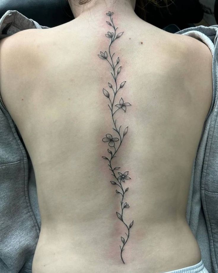 the back of a woman's lower back tattoo with flowers and leaves on it