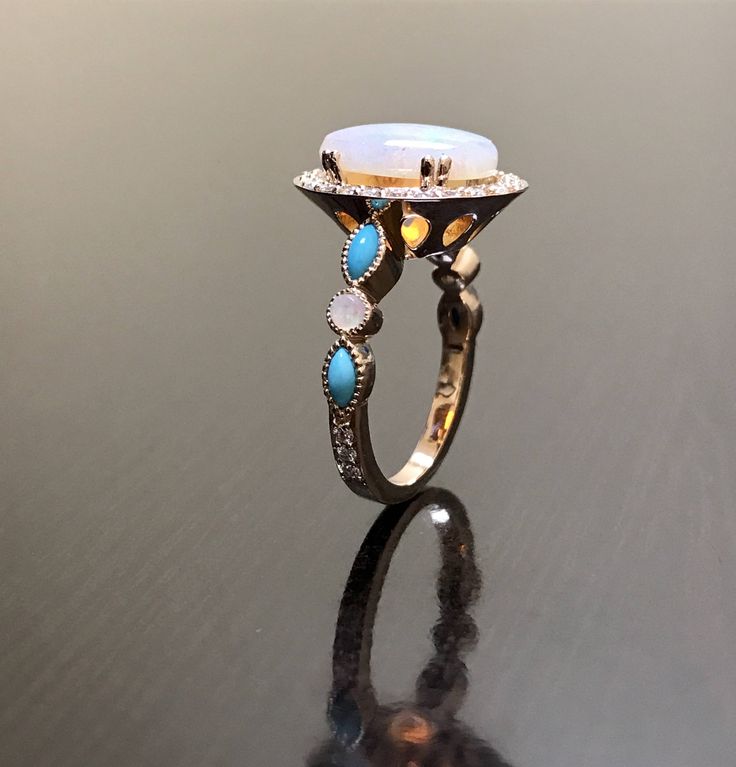 DeKara Designs Collection Metal- 14K Rose Gold, .583. Stones- Center Features an Oval Fiery Australian Opal Cabochon Cut 12 x 10 MM 2.20-2.50 Carats, Four Marquise Turquoise, Two Round Opals, 30 Round Diamonds F-G Color VS2 Clarity, 0.40 Carats. Size- 4-12 Beautiful Handmade Art Deco Inspired Turquoise Diamond Halo Opal Engagement Ring Made in 14K Rose Gold. This ring features a beautiful 12 x 10 oval shaped Australian Opal that is professionally set in between four double prongs. The opal is su Luxury Gold Turquoise Wedding Ring, Luxury Blue Turquoise Ring For Wedding, Heirloom Style Turquoise Ring For Wedding, Heirloom Blue Turquoise Wedding Ring, Turquoise Wedding Ring With Halo Setting, Heirloom Opal Ring With Gemstone Accents For Wedding, Gold Multi-stone Turquoise Ring For Wedding, Heirloom Turquoise Gemstone Ring For Wedding, Heirloom Turquoise Ring For Wedding