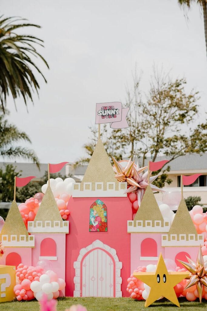 a pink and gold princess castle with balloons