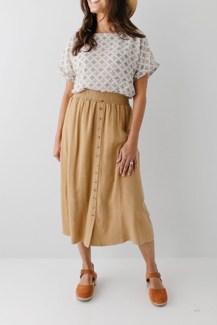 Start your day in style with the 'Greta' Skirt! This midi length, linen-blend skirt is light and airy for spring and summer and features button-down detailing for a fun touch. Pair the 'Greta' with all your favorite tops for Sunday morning or a day at the farmer's market! 30% Linen 70% Rayon Hand Wash Cold Hang to Dry Low Iron if Needed Do Not Dry Clean Fully Lined Model in Ochre Height 5'5" | Wearing Size Small Wearing 'Shalom' Geometric Print Top in Tan & 'Greta' Linen Blend Midi Skirt in Ochr Skirt And Blouse Outfits, Linen Skirt Outfit, Cotton Skirt Outfit, A Line Skirt Outfits, Clogs Outfits, Skirt Outfit Fall, Casual Mom Style, Linen Midi Skirt, Modest Clothes