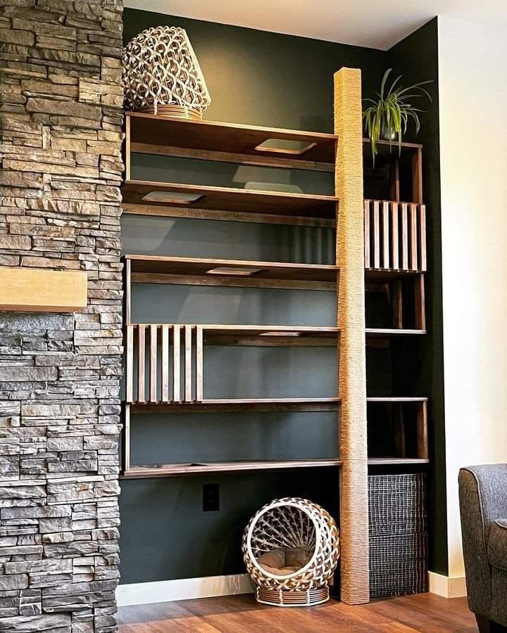 a living room with bookshelves and a chair in front of a stone fireplace