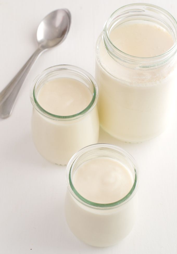 three jars filled with yogurt next to a spoon