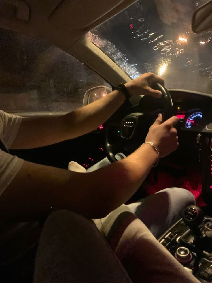 a man driving a car at night with the lights on