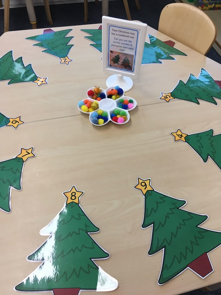 a wooden table with christmas trees painted on it and candy in the bowl next to it