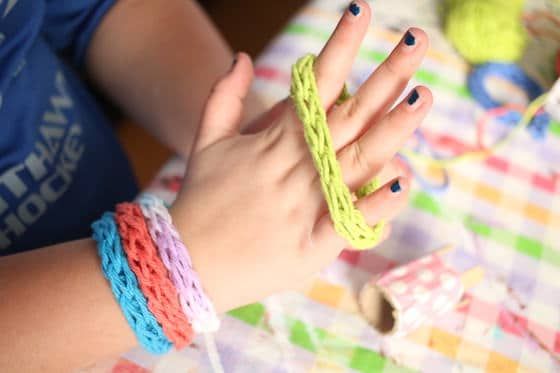 a woman's hand with multicolored crochet bracelets on it