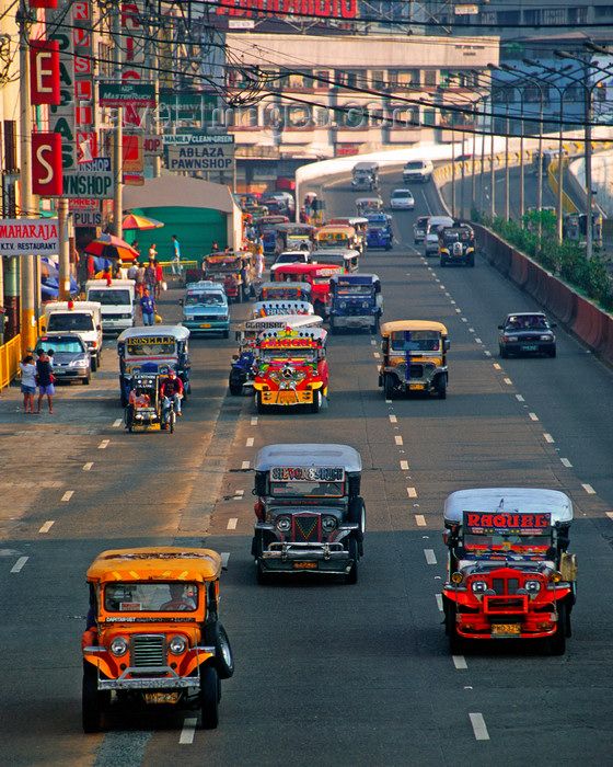 many cars are driving down the street in traffic on a busy city street with tall buildings