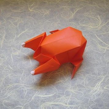 an orange origami animal sitting on top of a gray surface with swirly lines