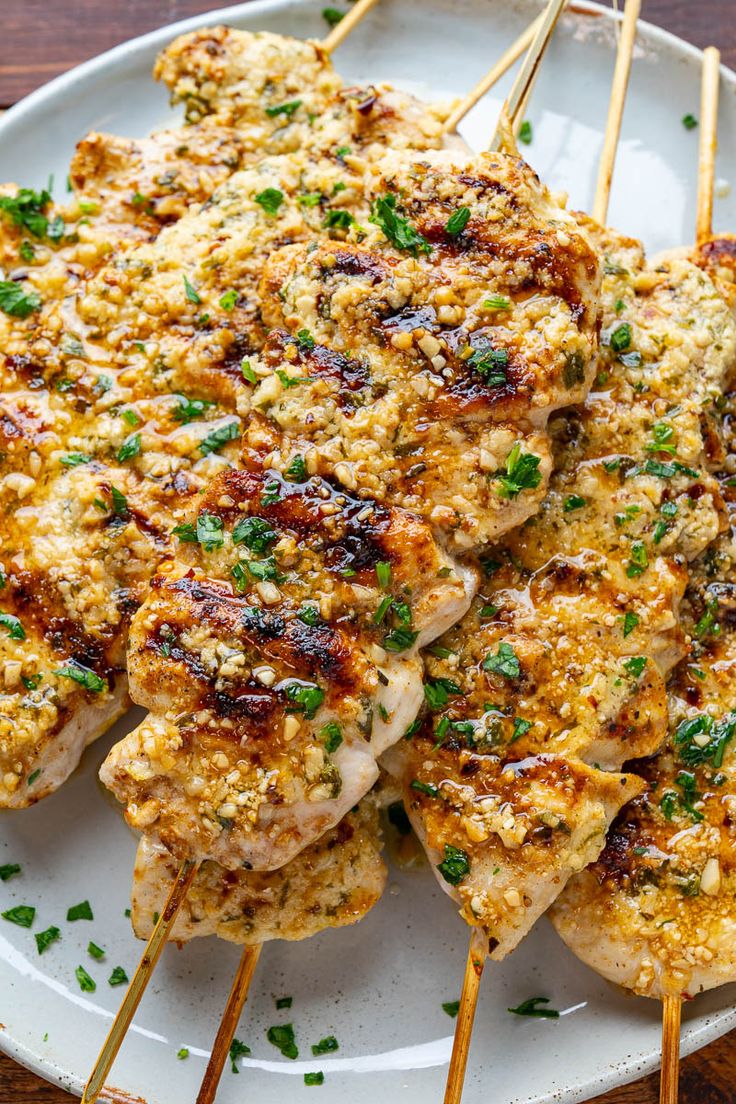 chicken skewers on a white plate topped with parsley