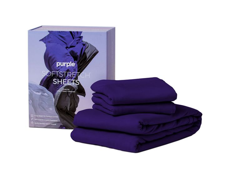 purple sheets are stacked on top of each other in front of a box and packaging