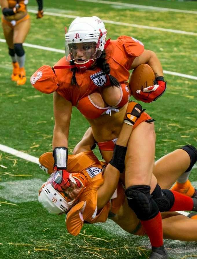 two women in orange uniforms playing football on the field