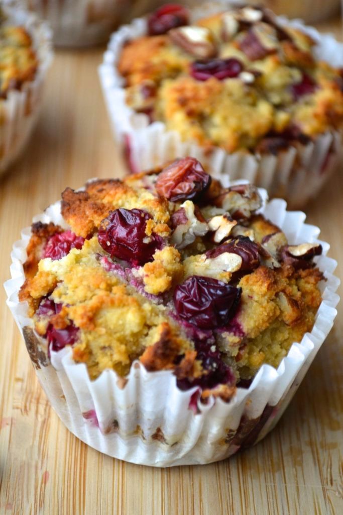 several muffins with cranberries and nuts in them on a wooden table