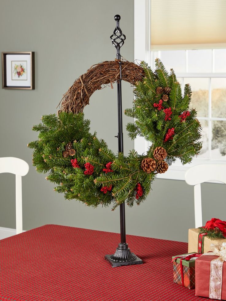 a christmas wreath sitting on top of a table next to a candle holder and presents