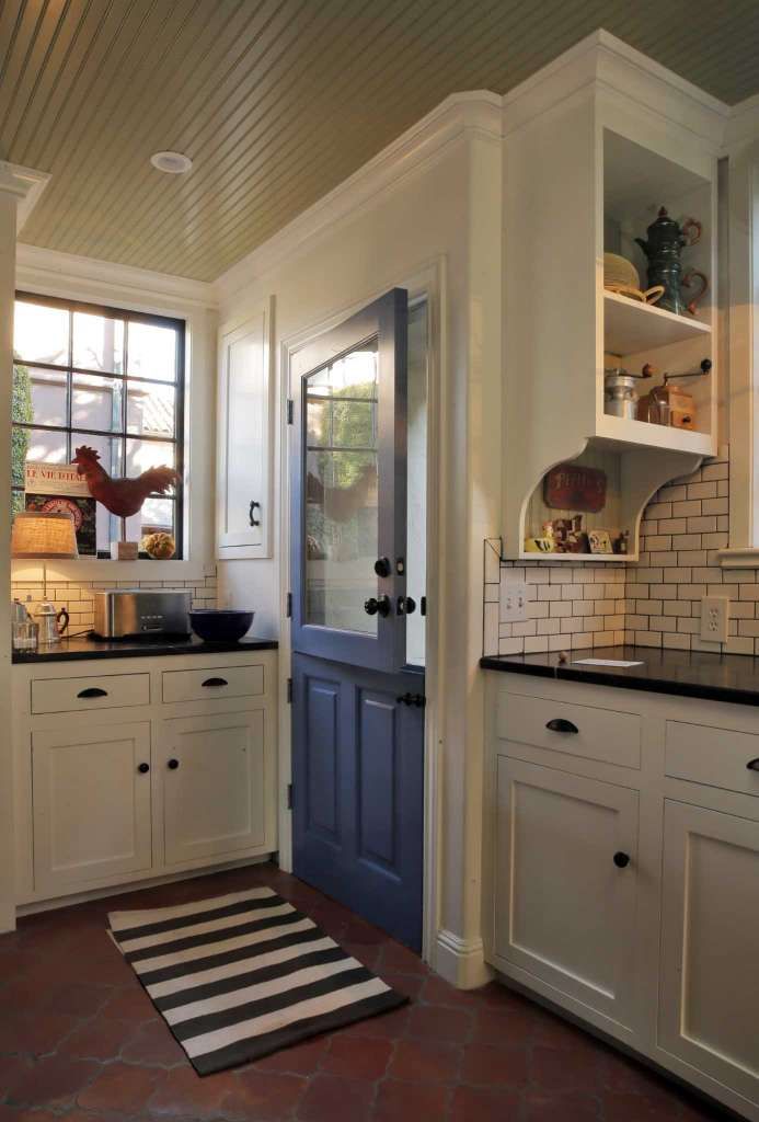 a kitchen with white cabinets and black counter tops next to a blue door in the center