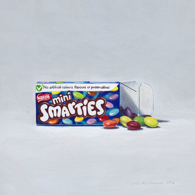 a box of mini smarties sitting on top of a white table next to some candies