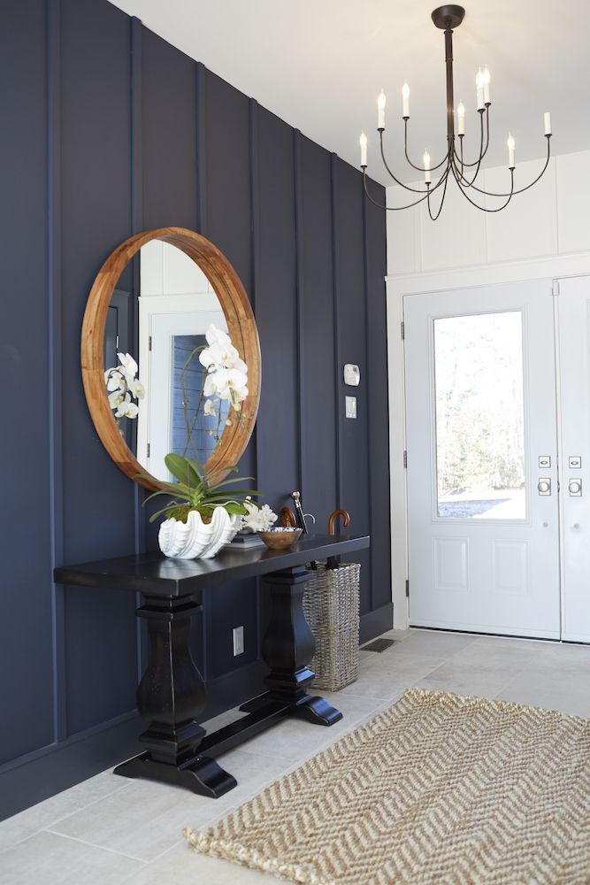 a hallway with a mirror, rug and chandelier