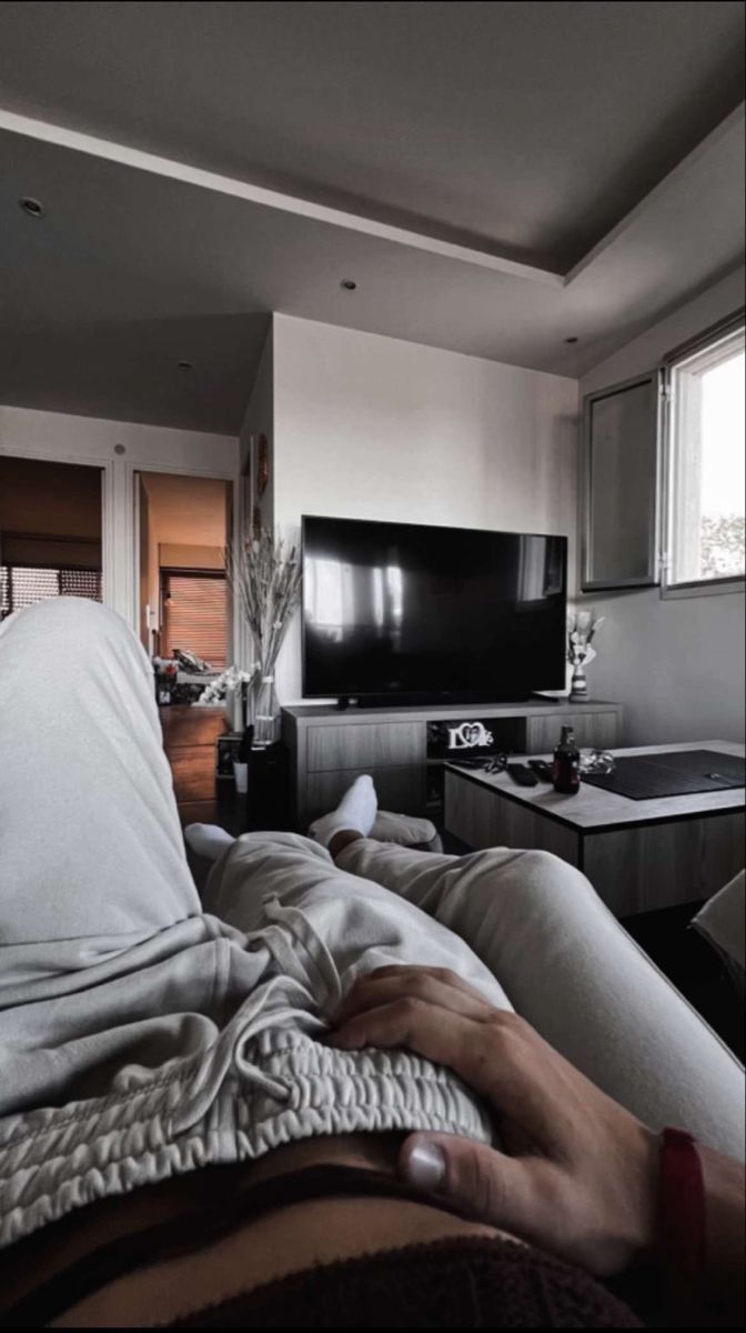 a person laying on a bed in front of a flat screen tv