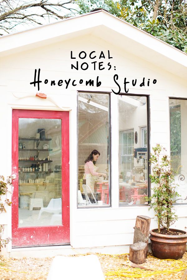 a woman standing in the window of a small white building next to a potted plant