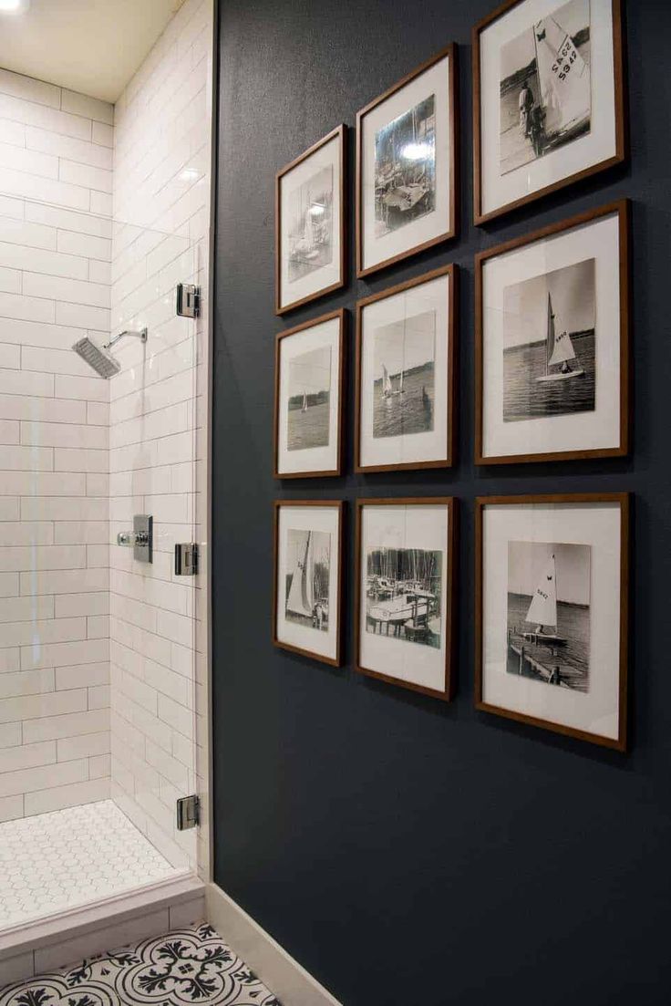 black and white photos hang on the wall above a shower in a bathroom with tile flooring