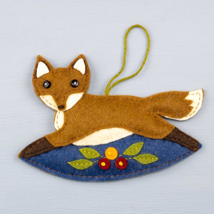 a felt ornament with a fox on it's back hanging from a string