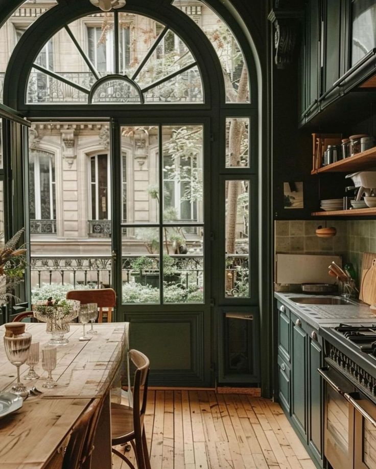 a kitchen with an arched window and wooden table in front of the stove top oven