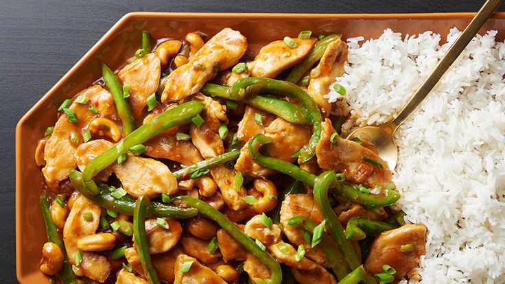 a plate with rice, chicken and green beans next to chopsticks on a table