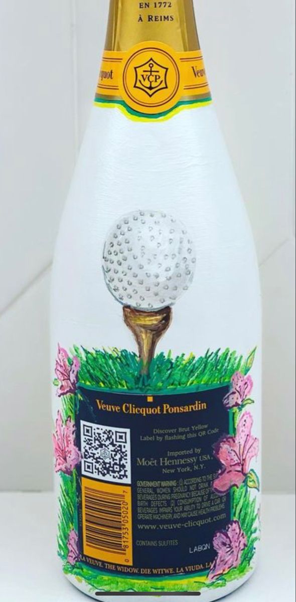 a bottle of wine with a golf ball on it's top and some flowers in the bottom