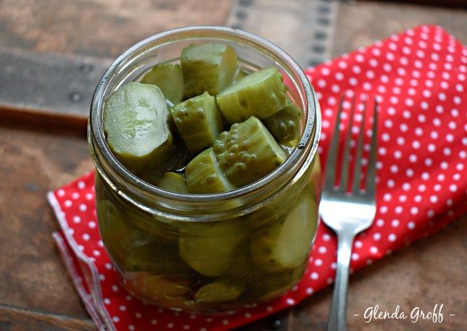 pickled cucumbers in a glass jar on a red napkin with a fork