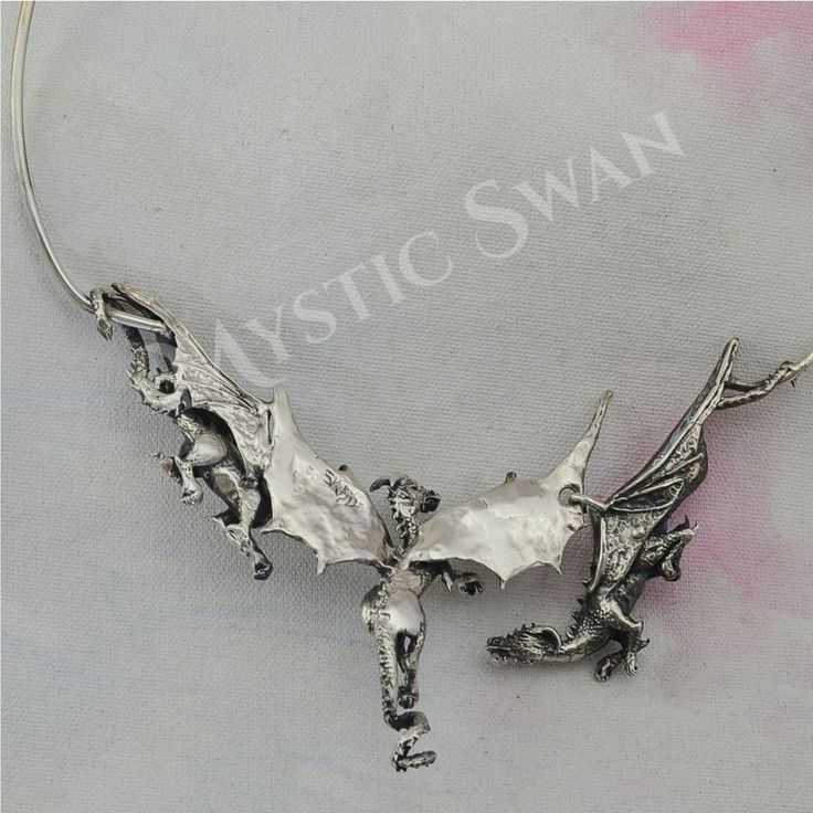 "Three magnificent dragons take flight in this stunning piece of sterling silver fantasy jewelry. The concept of the dragon necklace features three dimensional sculptures and an unique front clasp subtly incorporated into the design of the neckpiece; the result is a dragon trio statement necklace that seem to float around the wearer's neck, an artisan's creation that is sure to draw the eye of all who see it. Each of the dragons has a unique personality; the central dragon is the leader of the g Elegant Silver Jewelry For Fantasy Events, Silver Fantasy Jewelry With Dragon Design, Fantasy Silver Jewelry With Dragon Design, Silver Dragon Design Jewelry For Fantasy Events, Fantasy Style Silver Jewelry With Unique Design, Hand Cast Fantasy Sterling Silver Jewelry, Silver Pendant Jewelry For Fantasy Events, Silver Fantasy Necklace With Hand Cast, Unique Metal Jewelry For Fantasy Events