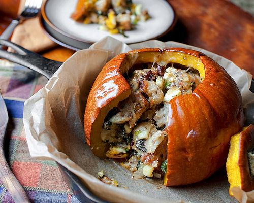 a stuffed pumpkin sitting on top of a table next to a plate filled with food