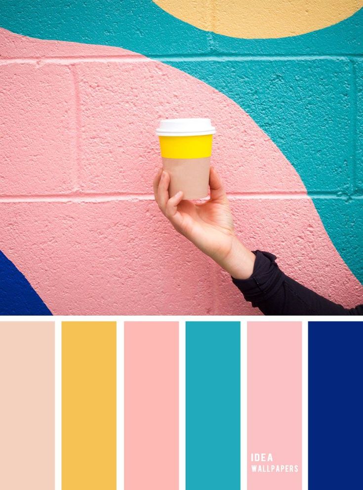 a person holding a cup in front of a pink and blue wall with yellow accents