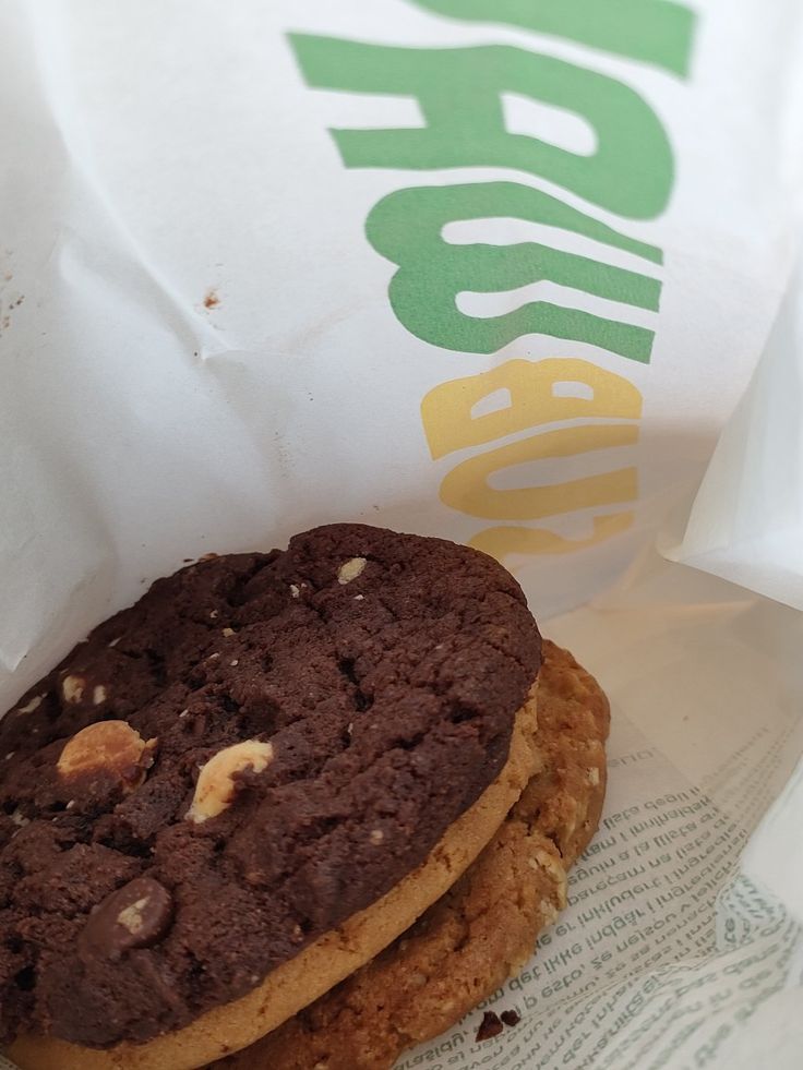 a chocolate cookie sandwich sitting on top of a paper bag next to a wrapper