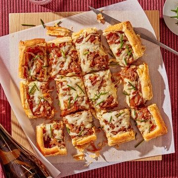 several small pizzas are on a table with wine glasses and utensils