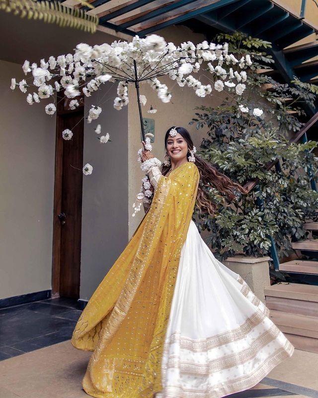 a woman in a yellow and white dress is holding an umbrella with flowers on it