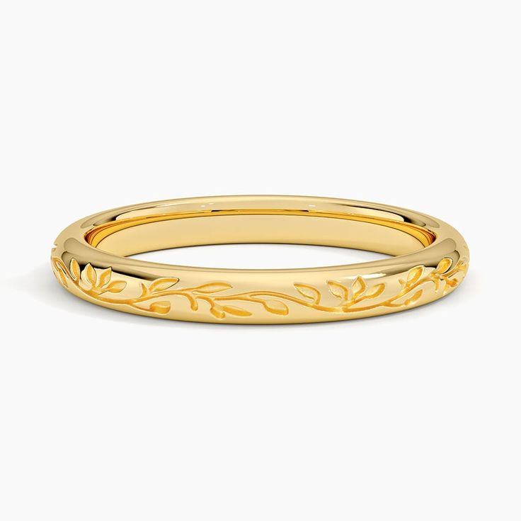 a yellow gold wedding band with leaves on the outside and an engraved design in the middle